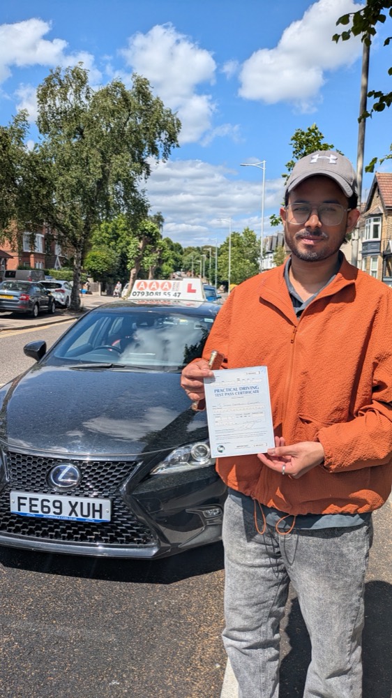 Auto Pass student holding his DVSA pass certificate next to the black Lexus tuition car